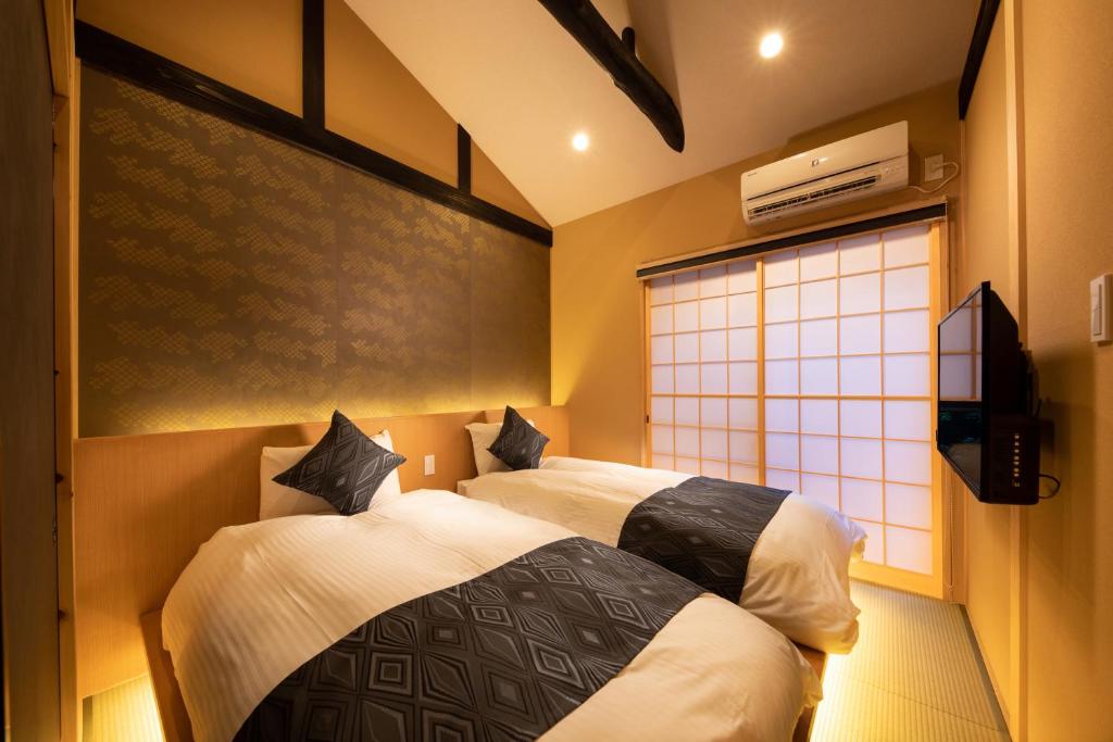 two beds in a room with a window at Kanade Kyotoeki-Minami in Kyoto