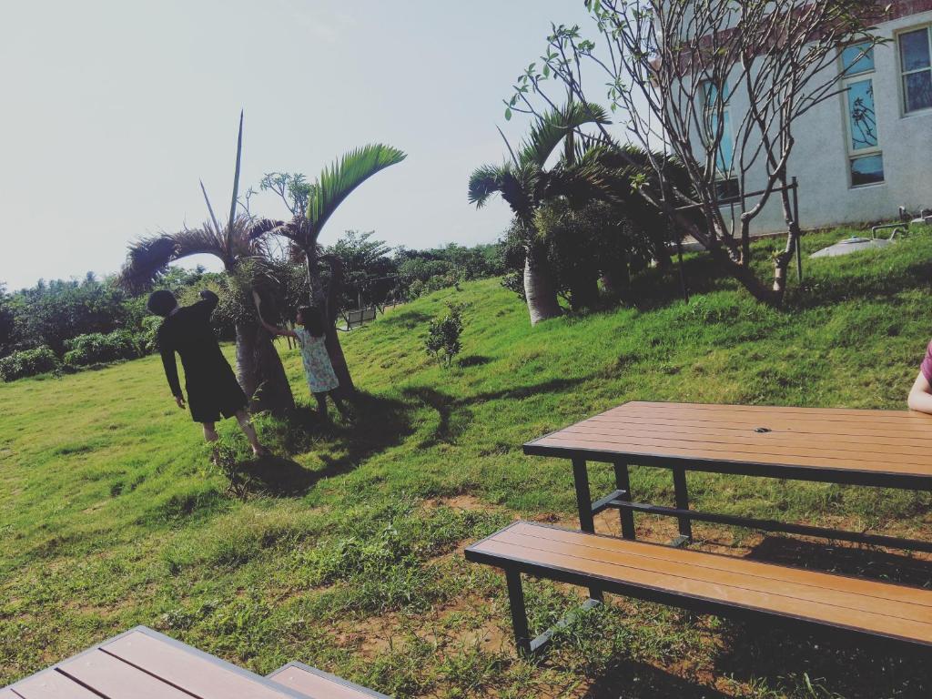 a woman standing in the grass next to a picnic table at Full Moon Resort in Hengchun