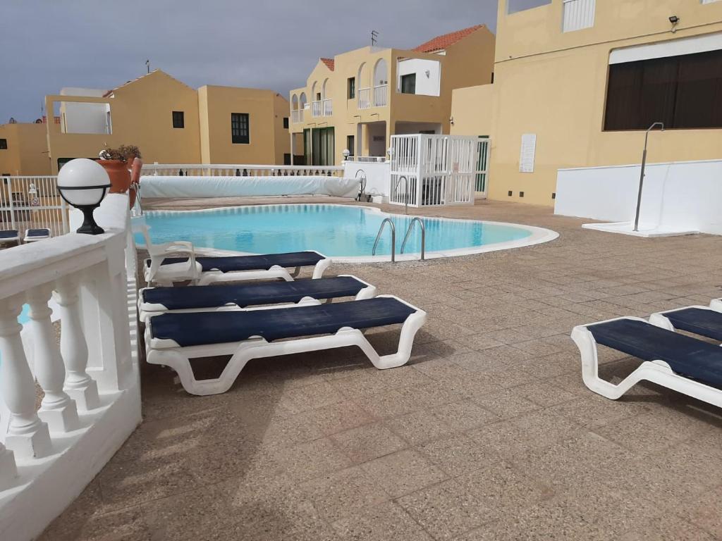 a swimming pool with two lounge chairs next to a building at Apartamento en Caleta Paraíso. in Costa de Antigua
