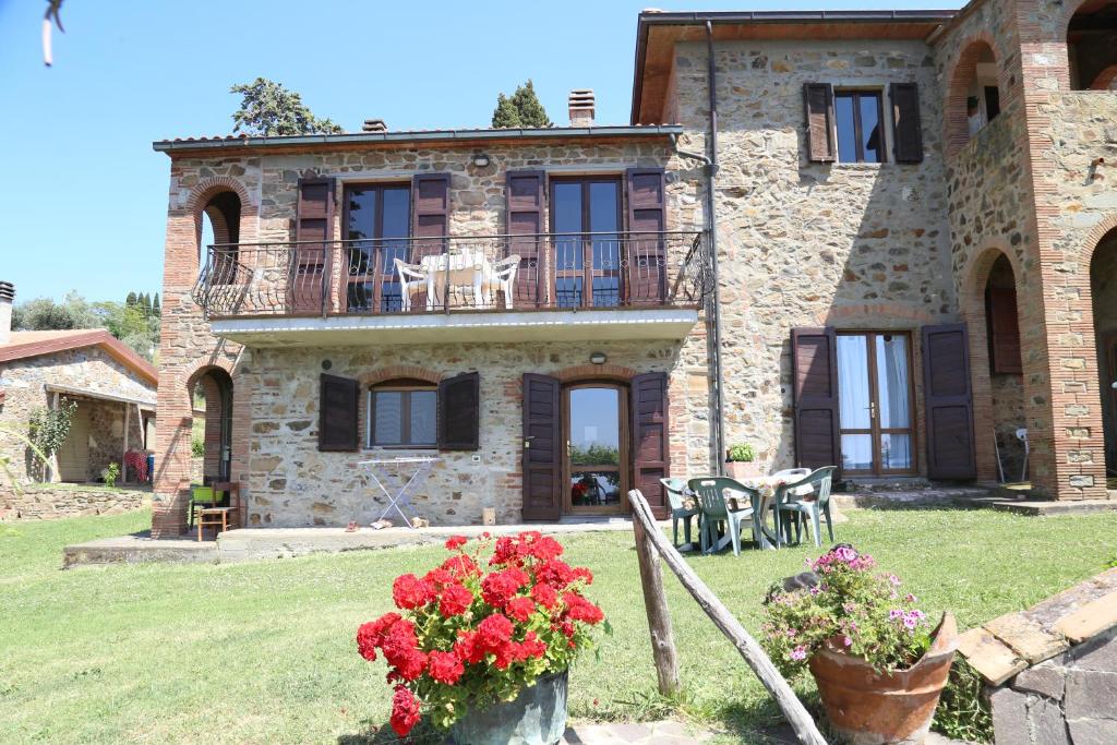 una grande casa in pietra con dei fiori di fronte di Agriturismo Bellavista apt La Pergola a Castagneto Carducci