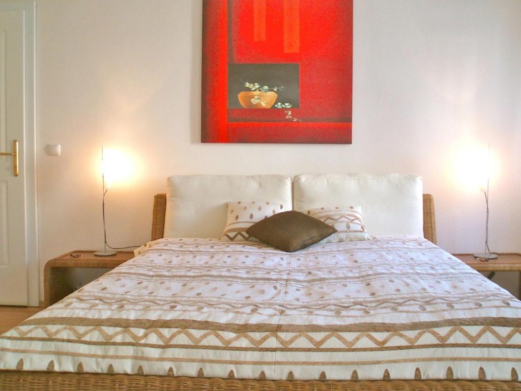 1 dormitorio con 1 cama con 2 lámparas y 1 pintura en Sonnberg Apartments, en Viena
