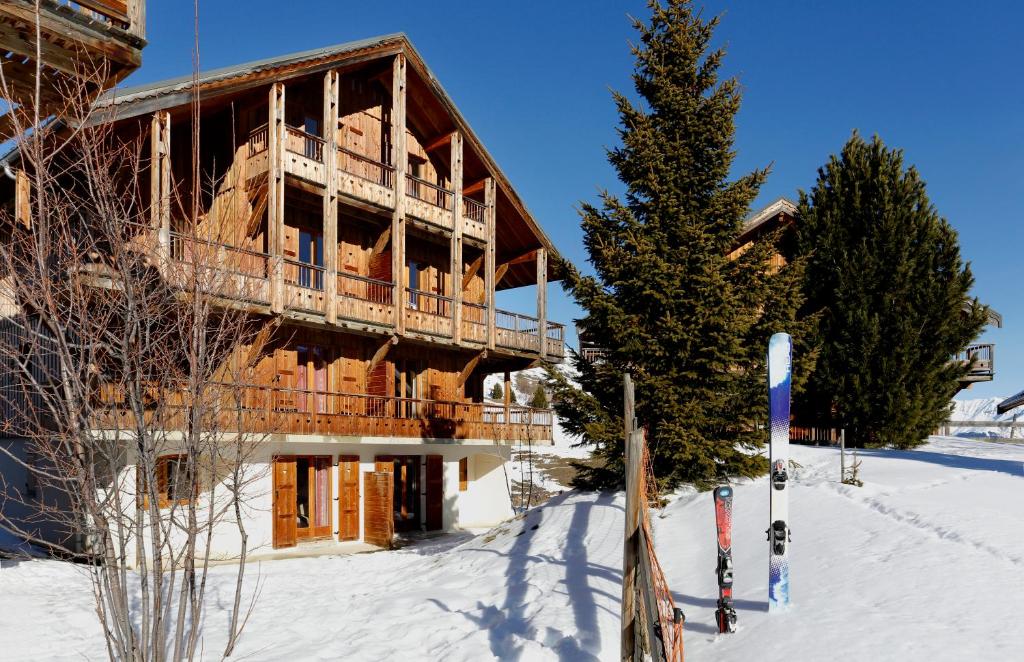 ein Gebäude im Schnee mit Skiern davor in der Unterkunft Résidence Néméa Les Chalets Des Cîmes in La Toussuire