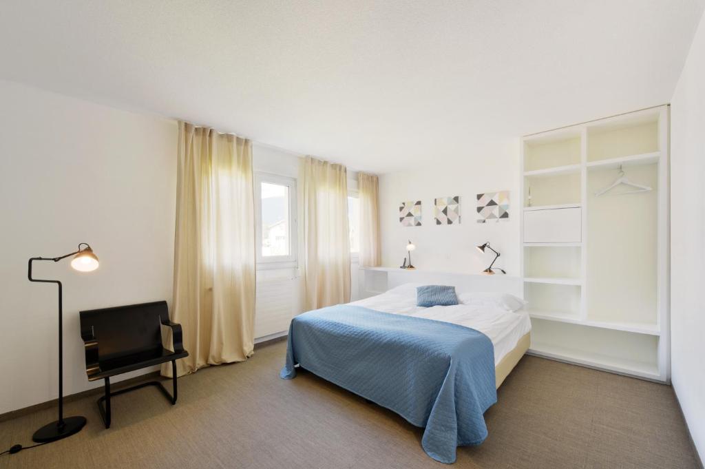 um quarto com uma cama e uma cadeira em Hôtel des Mosaiques em Orbe