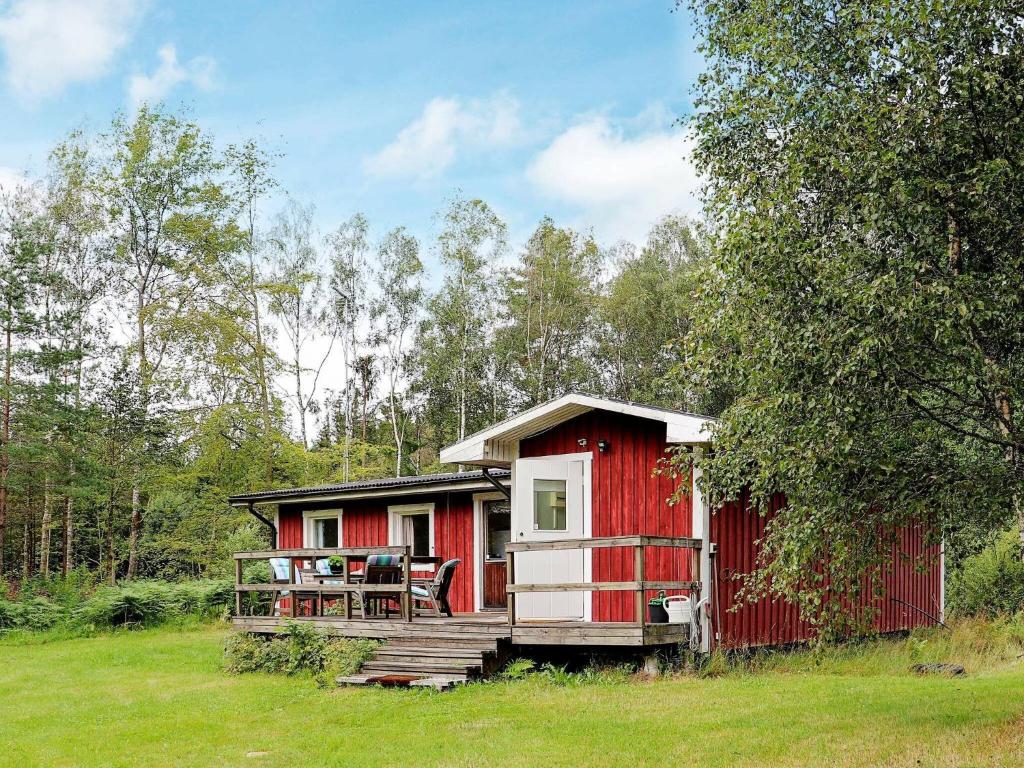 eine rote Hütte mit einer Veranda und einem Tisch darauf in der Unterkunft 4 person holiday home in RKELJUNGA in Orkelljunga