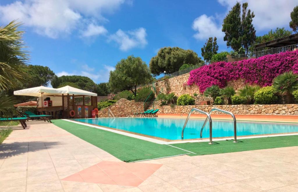 una piscina en un complejo con flores púrpuras en La Liccia - Camping&Village en Santa Teresa Gallura