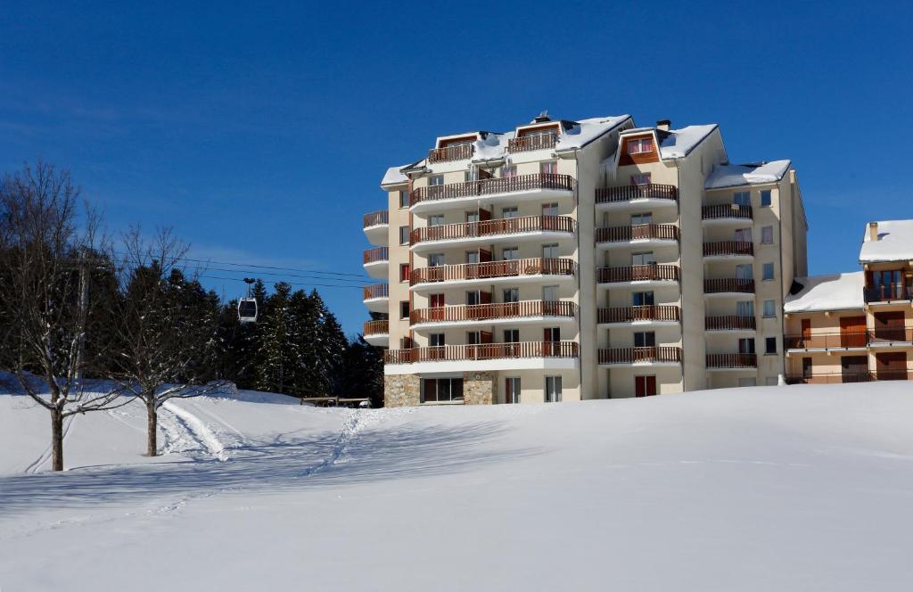 duży budynek apartamentowy w śniegu w obiekcie Résidence Néméa Les Balcons d'Ax w mieście Ax-les-Thermes