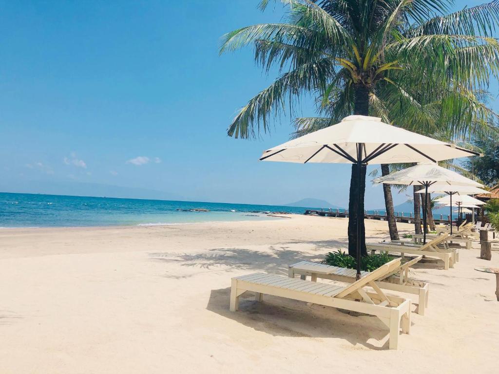 
a beach with a beach umbrella and palm trees at Gold Coast Resort Phu Quoc in Phú Quốc
