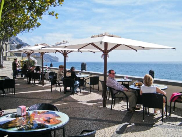 un grupo de personas sentadas en mesas bajo sombrillas en la playa en OLD TOWN Apartment W Interior Terrace - Barreirinha, en Funchal