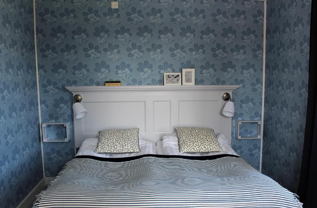 a bed with two pillows in a bedroom with blue wallpaper at STF Hostel Vilhelmina Kyrkstad in Vilhelmina