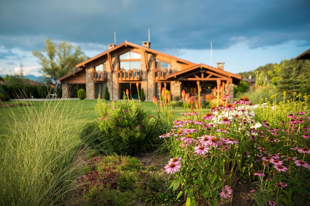 a wooden house with flowers in front of it at Luxury Chalet & Spa Tia Maria in Bansko