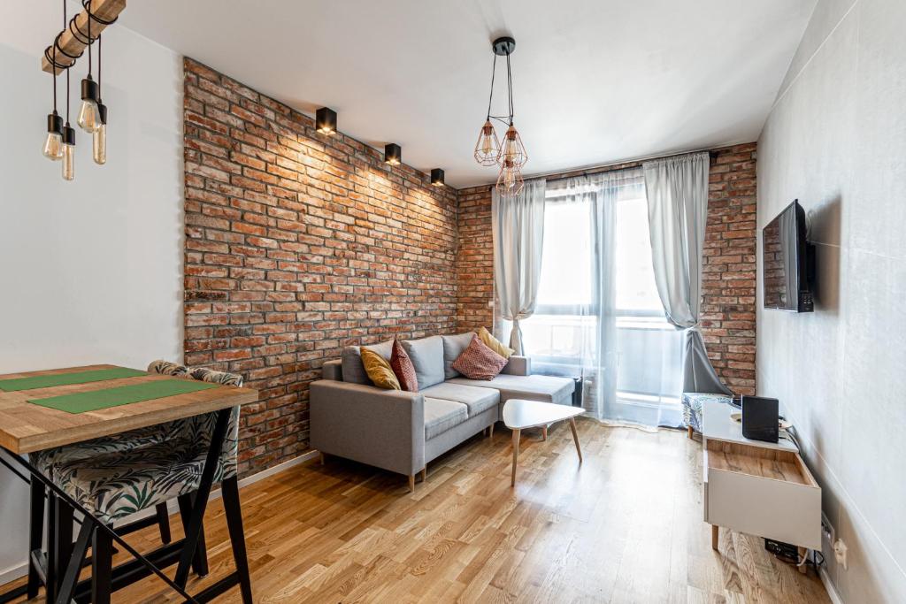 salon z kanapą i ceglaną ścianą w obiekcie Apartament OdraTower (wroc4night) we Wrocławiu