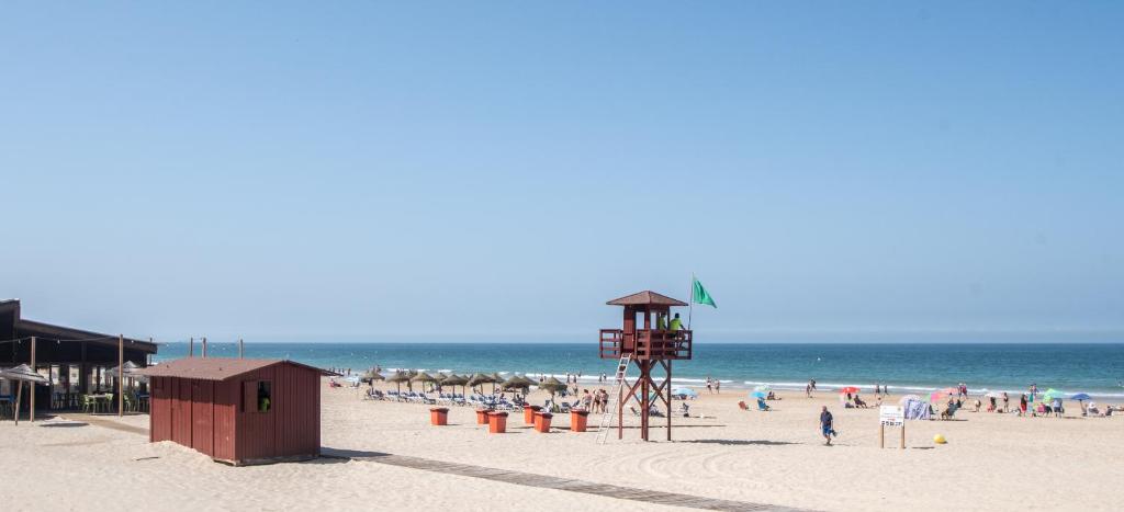 a beach with a lifeguard tower and a crowd of people at Apartamento La Terraza del Mar in Cádiz
