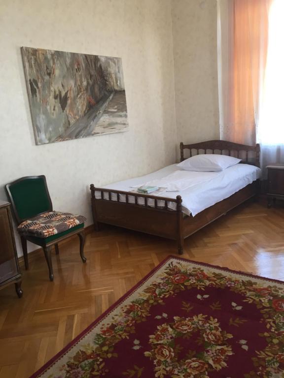 a bedroom with a bed and a chair and a rug at Alvanis veli in Nizhniy Alvani