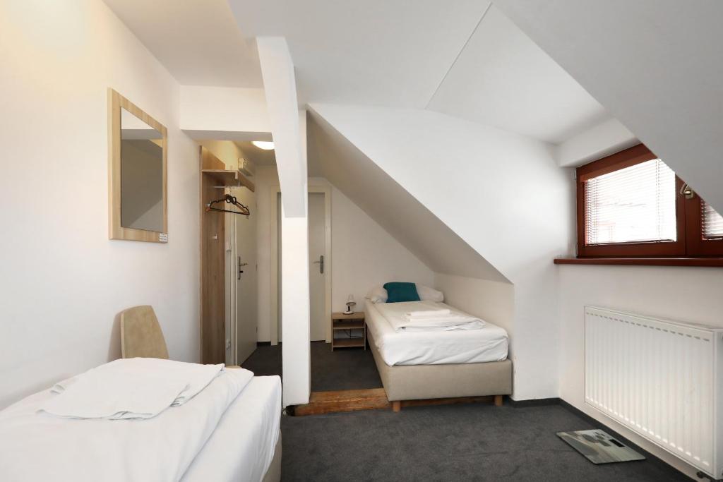 a attic room with two beds and a mirror at Pension U Tří sedláků in České Budějovice