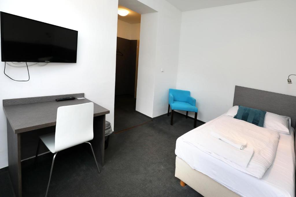 a bedroom with a bed and a desk and a tv at Pension U Tří sedláků in České Budějovice