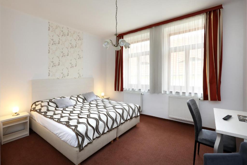 a bedroom with a bed and a desk and a window at Pension U Tří sedláků in České Budějovice