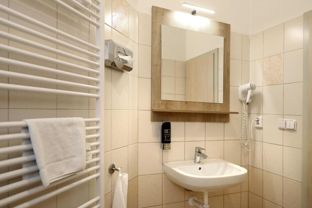a white bathroom with a sink and a mirror at Pension U Tří sedláků in České Budějovice
