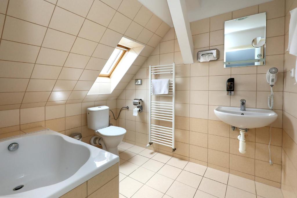 a bathroom with a tub and a toilet and a sink at Pension U Tří sedláků in České Budějovice