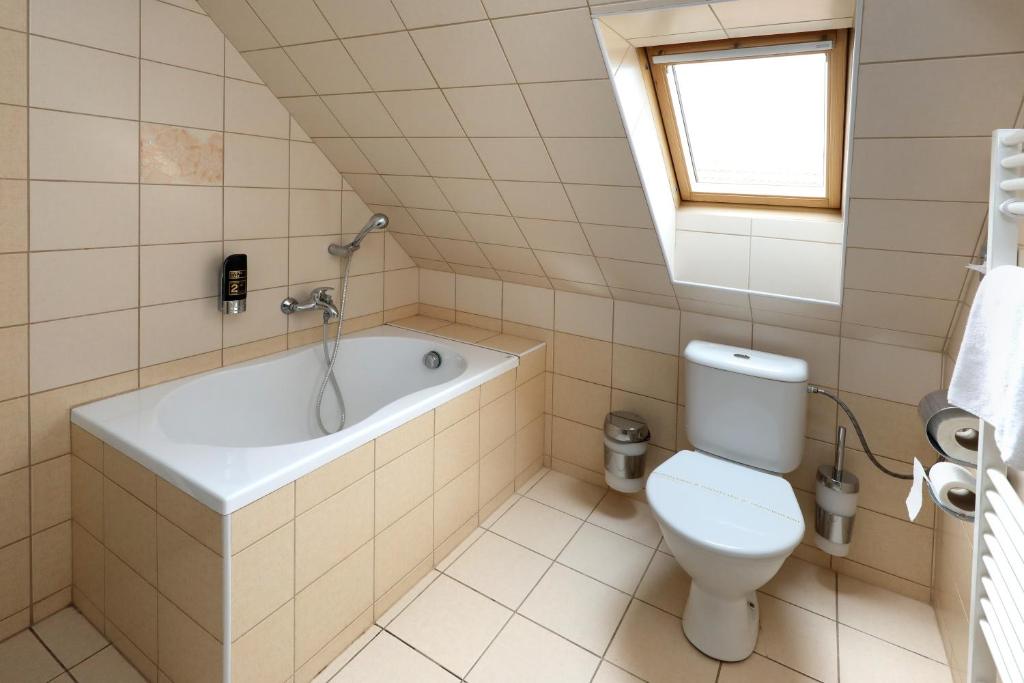 a bathroom with a tub and a toilet and a window at Pension U Tří sedláků in České Budějovice