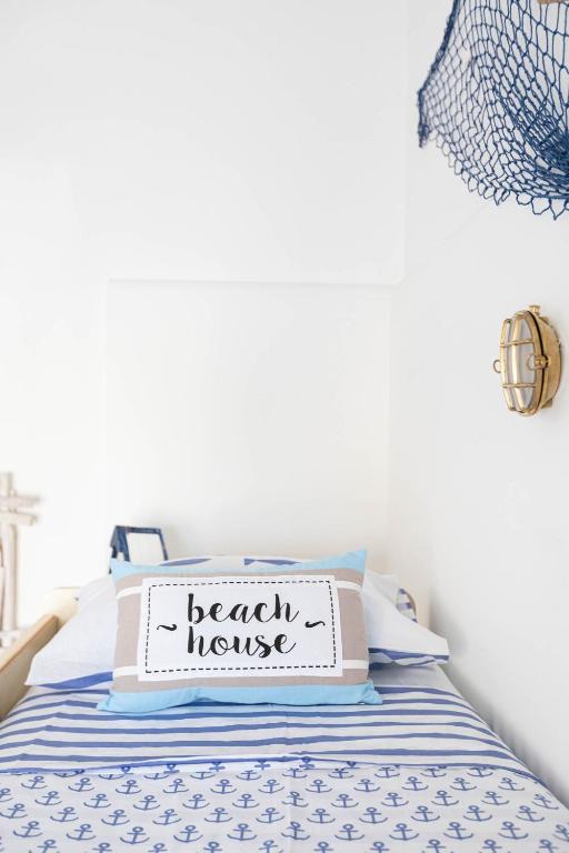 a bedroom with a bed with a beach house sign on it at Sea Elegance in Oliveri