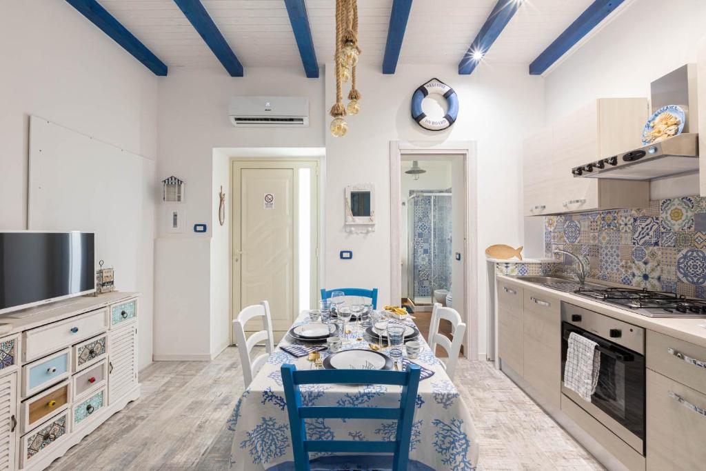 a kitchen with a table with blue chairs in it at Sea Elegance in Oliveri