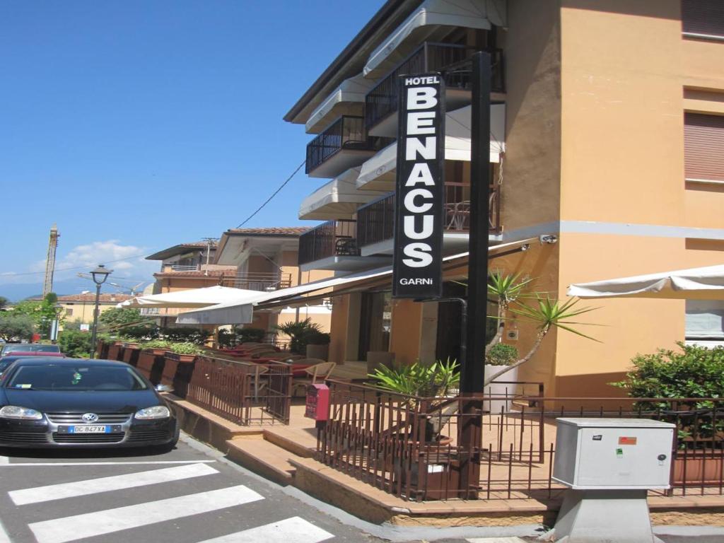 un'auto parcheggiata di fronte a un edificio con un cartello hotel di Hotel Benacus a Bardolino