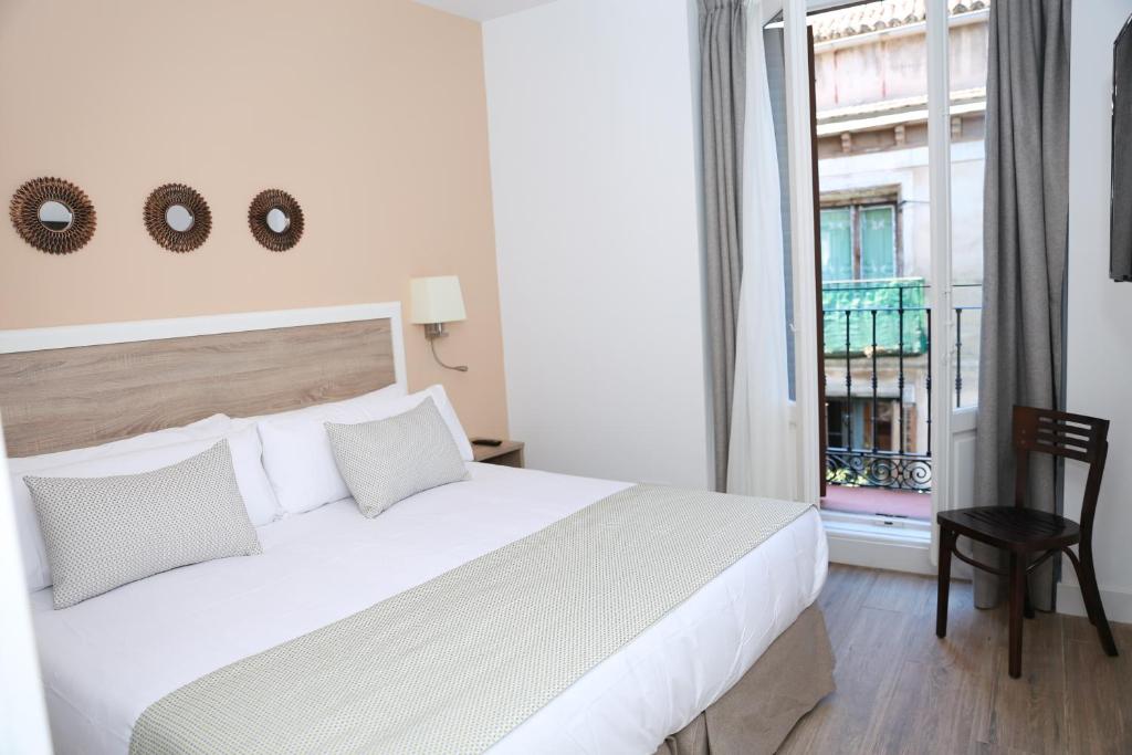 una camera da letto con un grande letto bianco e una finestra di New Point Opera a Madrid