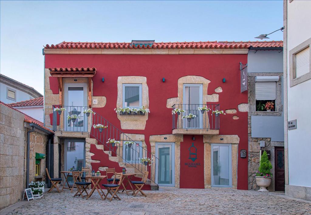 een rood gebouw met tafels en stoelen ervoor bij Hostel Bulwark in Valença