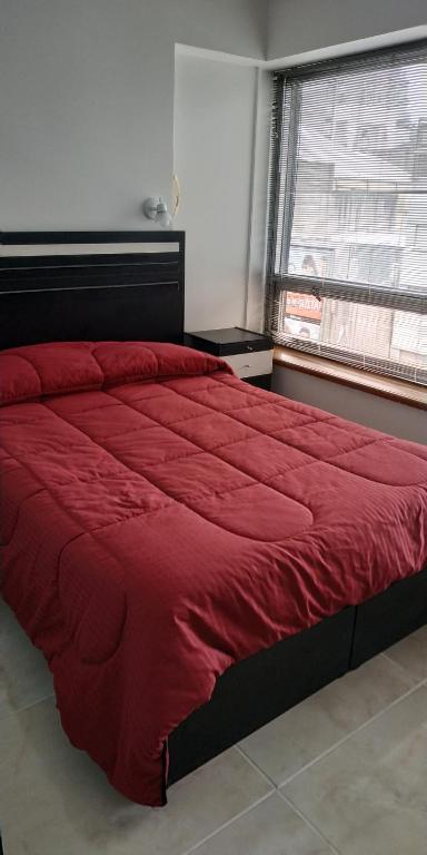 een groot rood bed in een slaapkamer met een raam bij Departamento en Apart hotel, Excelente ubicación en Microcentro in Buenos Aires