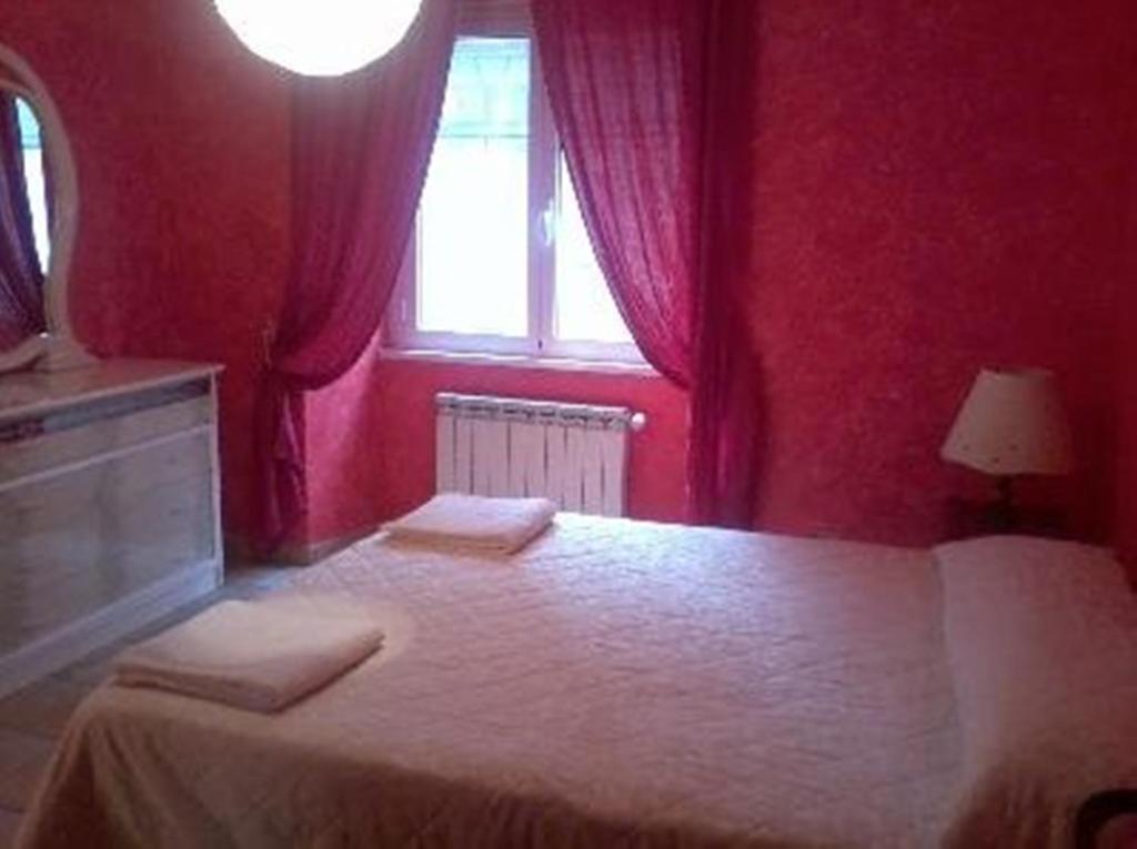 een slaapkamer met een bed met rode muren en een raam bij Max House in Rome