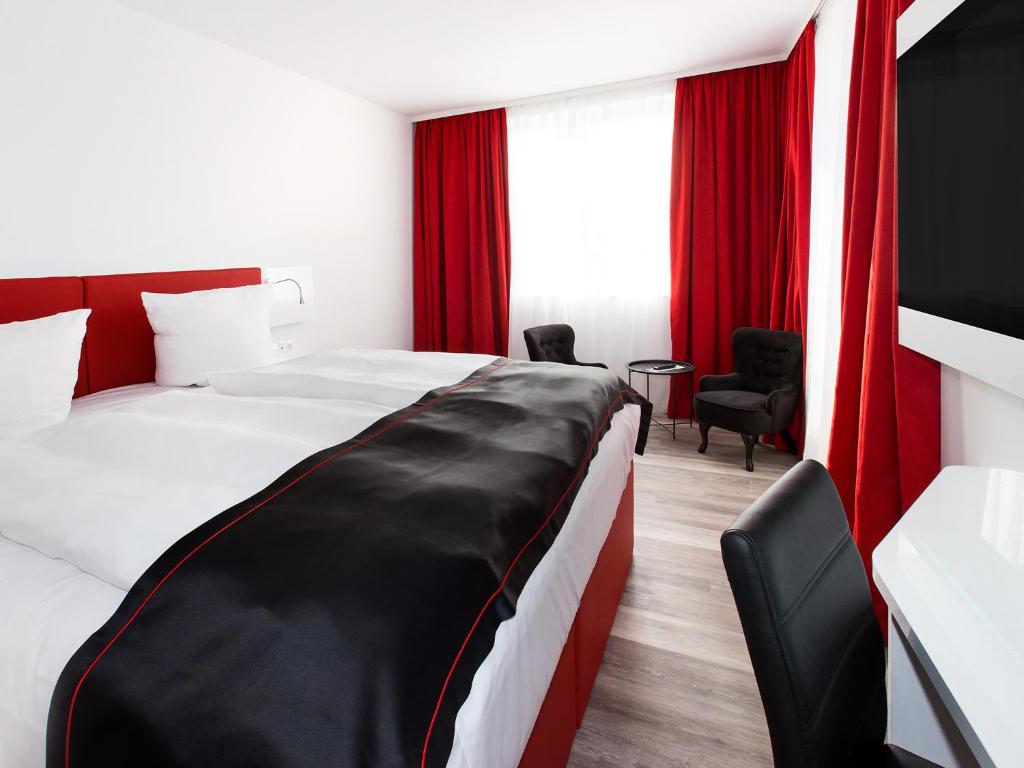 a hotel room with a large bed with red curtains at DORMERO Hotel Salzgitter in Salzgitter