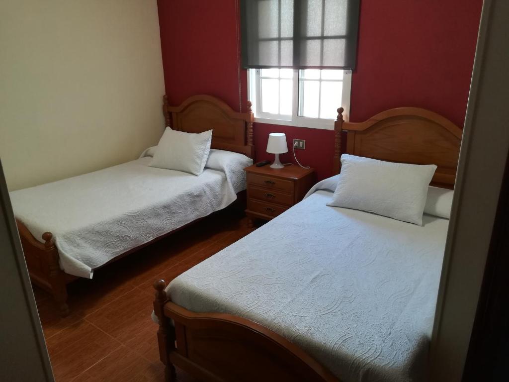 2 camas en una habitación con paredes rojas en Pensión Restaurante Casa Camiño II, en Palas de Rei 