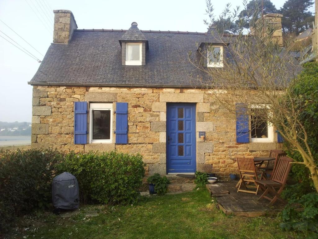 une maison en pierre avec une porte bleue et deux chaises dans l'établissement maison de pêcheurs, à Saint-Michel-en-Grève