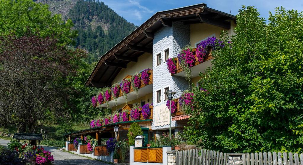 a building with flowers on the side of it at Pension Appartements Kirchenwirt in Döbriach