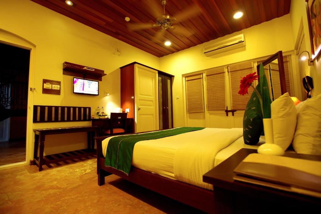 a bedroom with a bed and a table and a television at Tea Bungalow in Cochin