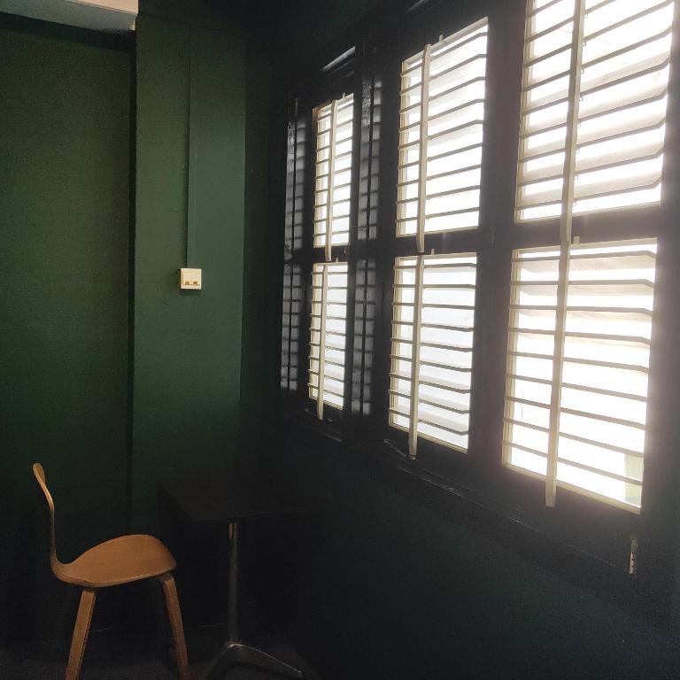 a chair sitting in a room with windows at Wink at Mosque Street in Singapore