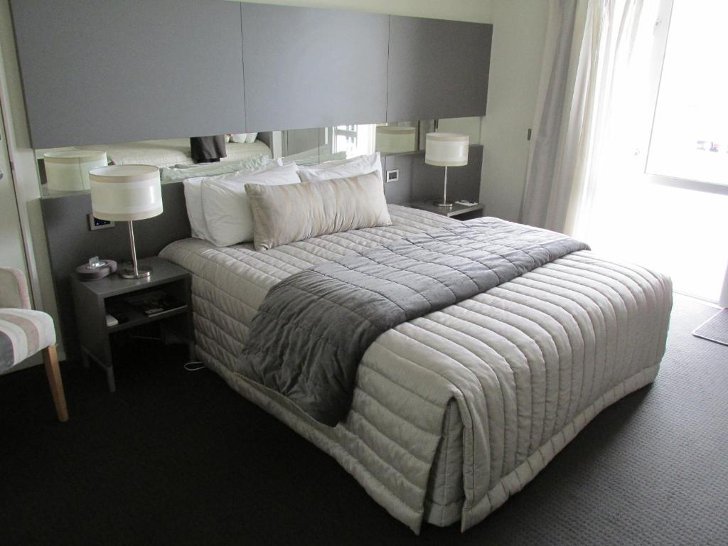 ein großes Bett in einem Hotelzimmer mit zwei Lampen in der Unterkunft Airport Gateway Motor Lodge in Christchurch