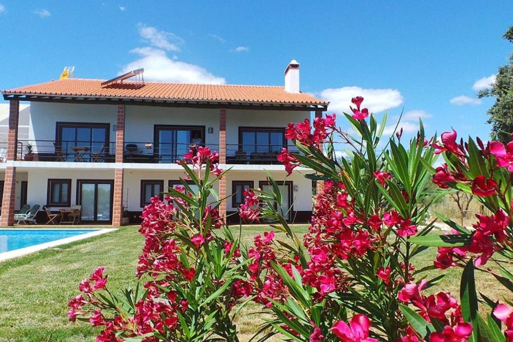 a villa with a swimming pool and pink flowers at Monte das Matas in Monsaraz
