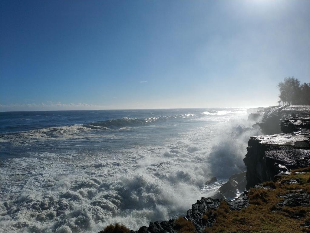 une grande vague océanique percutant une rive rocheuse dans l'établissement Ocean Breeze Inn, à Keaau