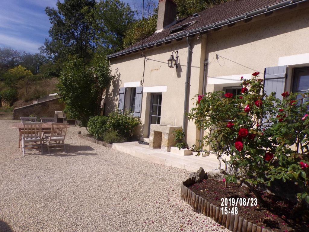 un edificio con una mesa, bancos y flores al lado en Le Troglo des Renaudières, en Azay-le-Rideau