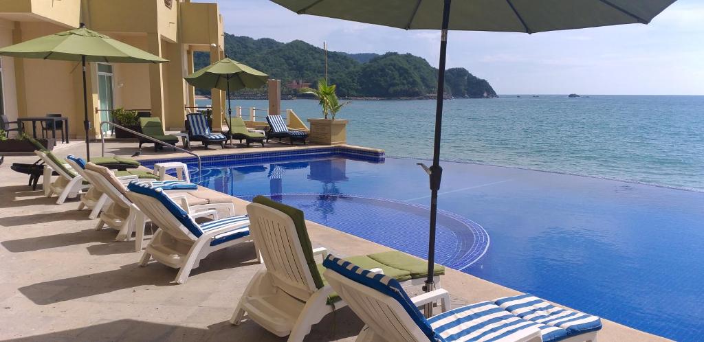 a row of chairs and umbrellas next to a swimming pool at Hotel Bogavante in Barra de Navidad