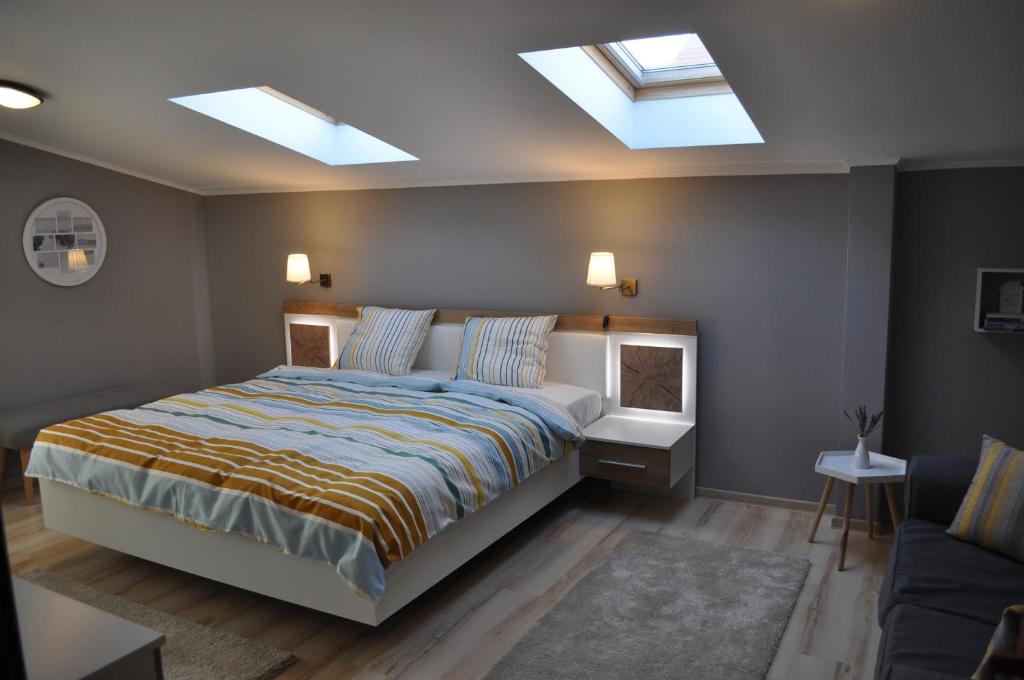 Schlafzimmer mit einem Bett und Oberlichtern in der Unterkunft Sleep & Fly Apartment in Otopeni