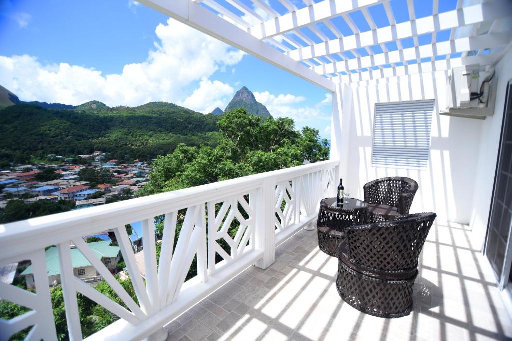 a balcony with a table and chairs and a view of the mountains at Sugarmon Villas in Soufrière