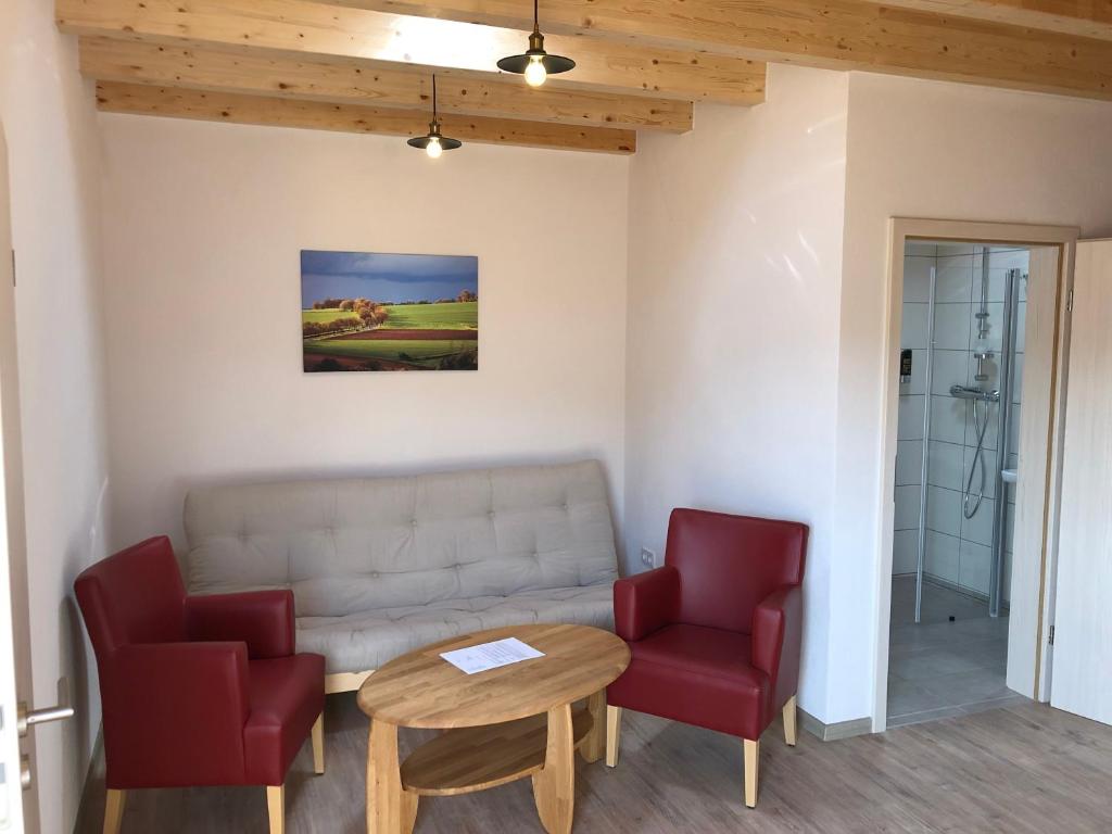a living room with a couch and two red chairs at Carolinger Hüttendorf in Weyer