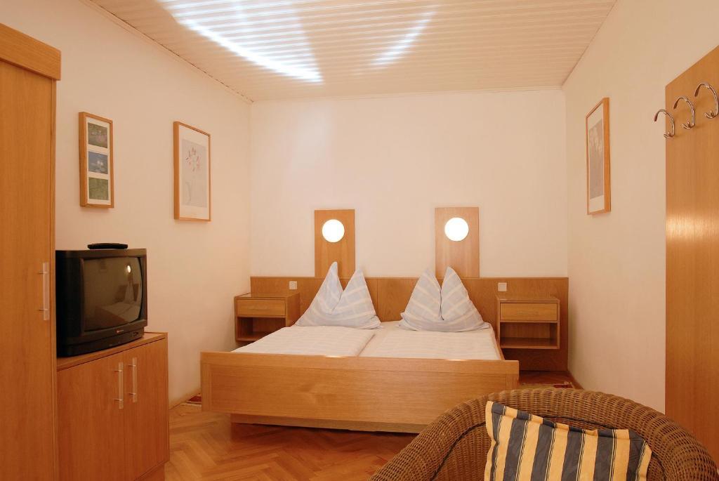 a bedroom with a bed with white pillows and a tv at Madar Café Central Melk in Melk