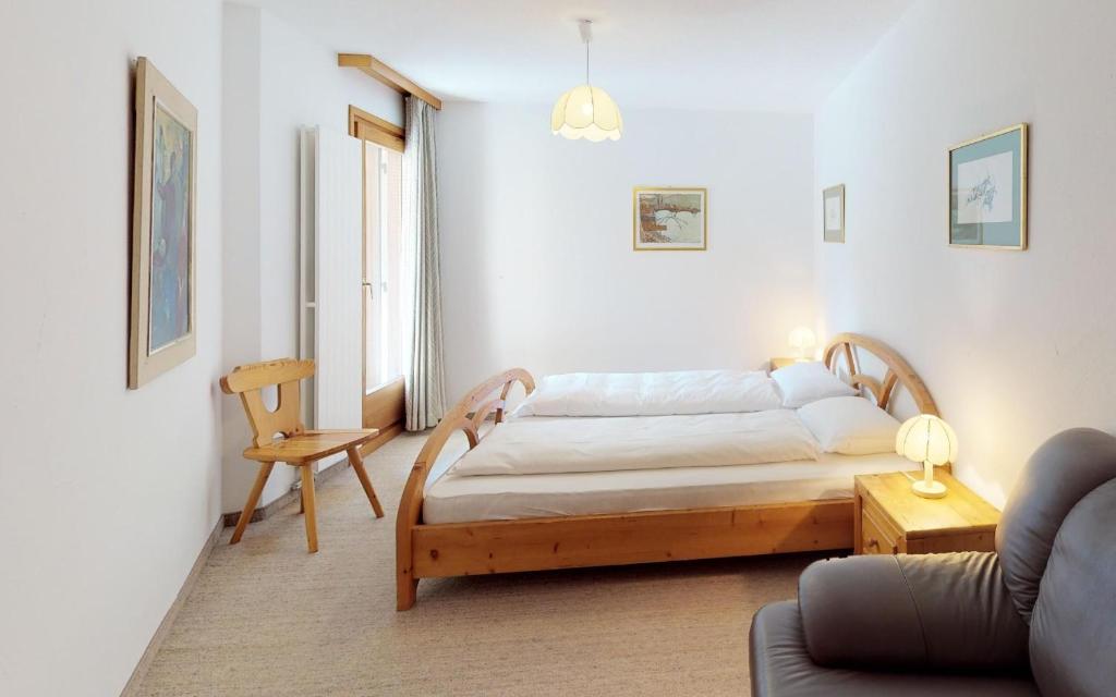サンモリッツにあるLudains 6のベッドルーム1室(ベッド1台、椅子、ソファ付)