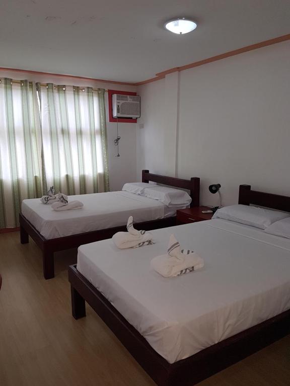 una camera d'albergo con due letti con lenzuola bianche di Catalina`s Inn family room a Panglao