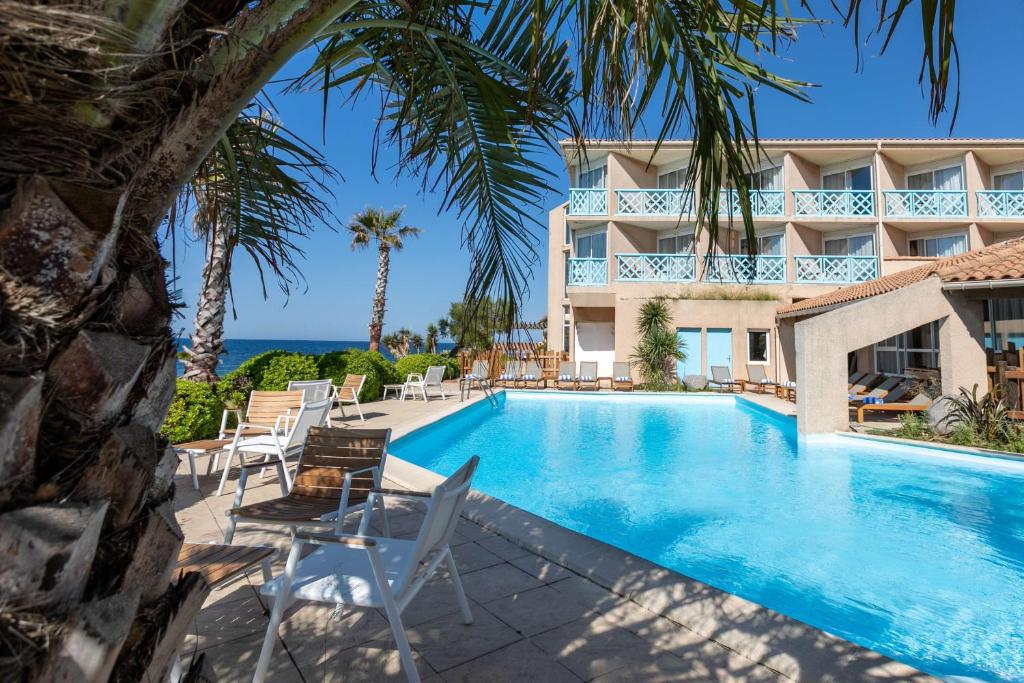 a swimming pool in front of a hotel with palm trees at Hotel Paradou Mediterranee, BW Signature Collection by Best Western in Sausset-les-Pins