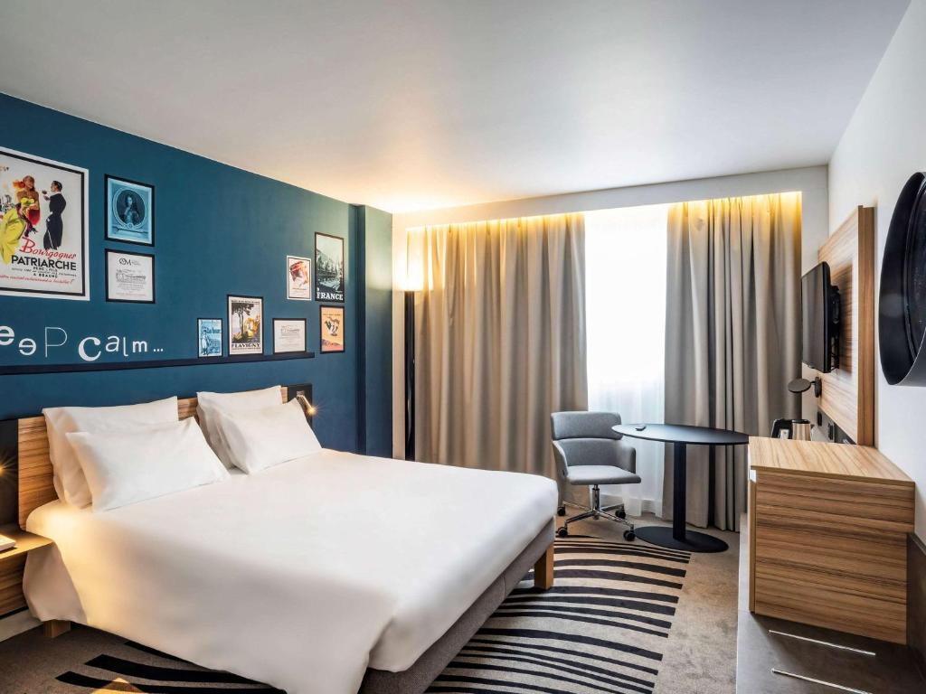 a hotel room with a bed and a desk at Novotel Beaune in Beaune