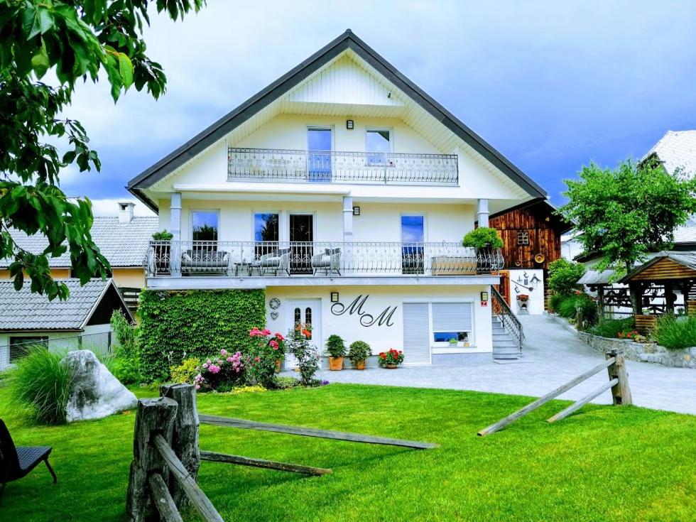 a white house with a balcony and a yard at Barn House MM in Bled